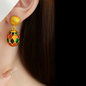 Close-up of vintage golden oval enamel earrings showing elegant retro style on model