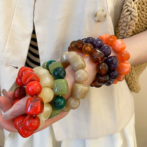 Gros plan d'un mannequin portant des bracelets en perles acryliques marbrées colorées