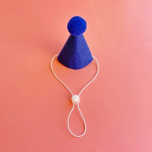 Close-up of blue felt pet party hat with matching pompom and adjustable elastic strap