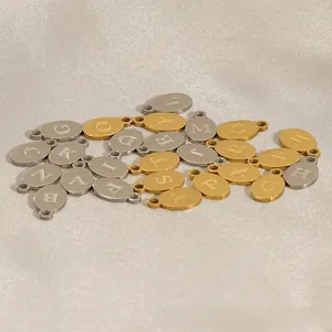 Detailed close-up of gold and silver oval alphabet charms for DIY jewelry making