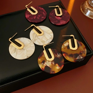 Detail of round acetate earrings in red marble, white shell, and tortoiseshell patterns