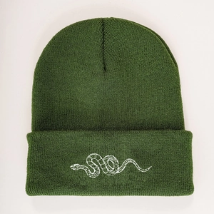 Close-up of deep green knit beanie featuring a white snake embroidery and ribbed texture