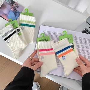 Detail of college style mid-tube socks with stripes and embroidered smiley face patch