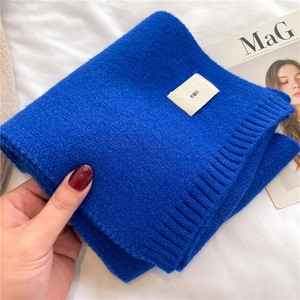 Close-up of blue knitted scarf with soft wool texture and a small beige brand label