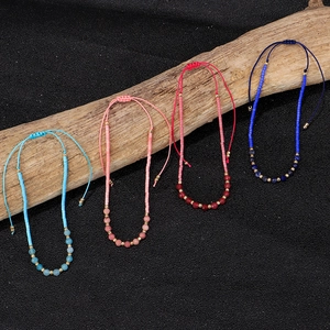 Handgemaakte 2mm stenen kralen armbanden in vier kleuren op een stuk drijfhout