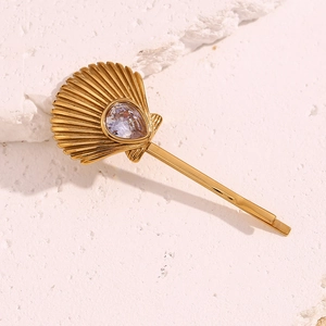 Detail of a gold scallop hair clip with a drop-shaped zircon on a textured stone