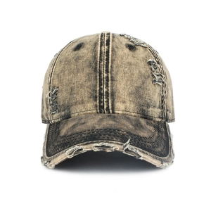 Close-up detail of vintage distressed denim baseball cap with frayed holes and worn texture