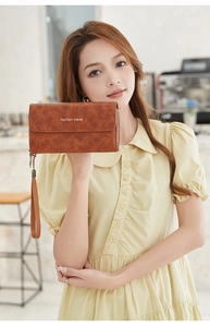Dettaglio della pochette vintage in pelle marrone con scritte dorate e cinturino da polso