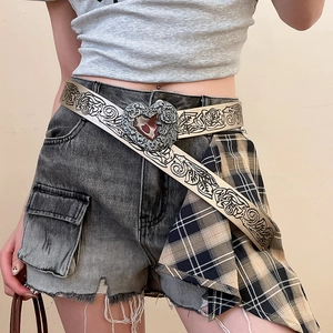 Detail of vintage heart buckle with rose relief and floral embossed leather belt texture