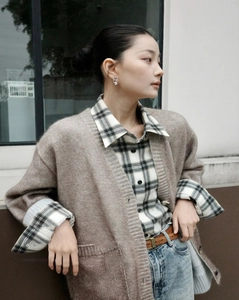 Close-up of brown mohair cardigan layered with plaid shirt and blue jeans in street style