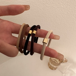 Close-up of five high-elasticity hair ties with matte gold metal buckles on a wrist