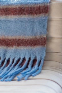 Close-up of blue and brownish-red striped boucle scarf with braided fringe details