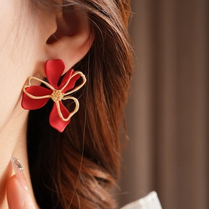 Close-up of vintage red flower earrings with gold edges worn on an earlobe