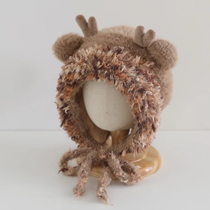 Detailed view of the plush reindeer earflap hat with 3D antlers and soft pom-poms