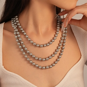 Close-up of triple-strand grey faux pearl necklace worn by a model for elegant vintage styling