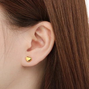 Gros plan détaillé d'une boucle d'oreille cœur dorée polie portée par un mannequin de mode
