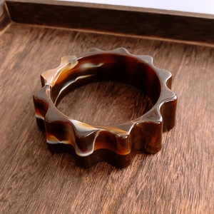 Détail macro du bracelet en résine ambrée aux motifs marbrés et bords en forme d'engrenage