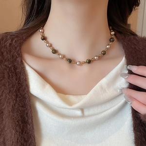 Close-up of tiger eye and pearl mixed bead necklace on model neck with brown knit cardigan