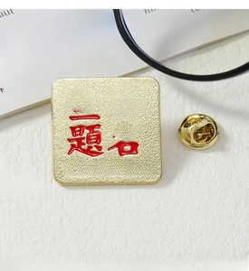Close-up of golden square metal badge with embossed red Succeed in the Examination text