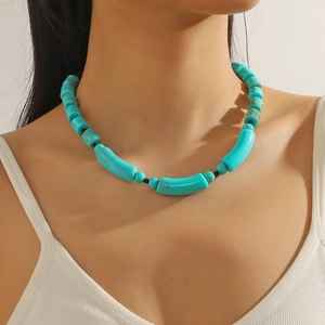 Detail shot of turquoise beaded necklace featuring irregular tube beads on model's neck