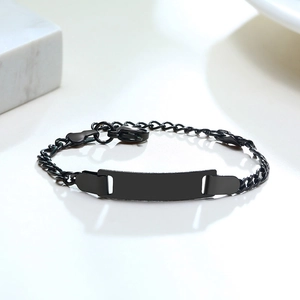 Macro shot of matte black stainless steel plate bracelet for kids on white marble surface
