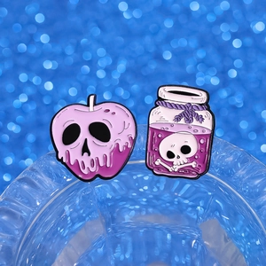 Macro detail of gothic poison apple and skull potion bottle enamel pin set