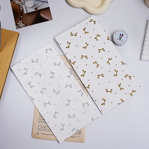 Detail of paper gift bags with elegant gold and silver bow patterns on a clean white background