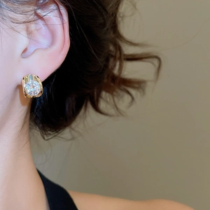 Close-up of 18k gold plated stud earrings with sparkling cubic zirconia on a model