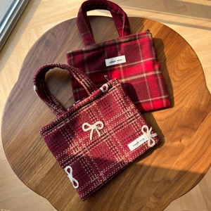Vue détaillée des sacs en laine à carreaux rouges avec étiquettes et nœud blanc tissé