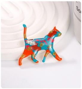 Close-up of a colorful enamel cat brooch with vibrant red, blue and glitter finish