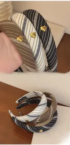 Detail of vintage striped sponge headband showing golden heart charm and handmade label