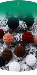 Detail of red flocked and textured Christmas ornaments hanging on a snowy pine branch