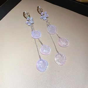 Detailed macro view of floral resin drop earrings with crystal studs on gold tray