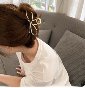 Detailed view of a golden metallic bow hair claw clip worn on a model in a cozy setting