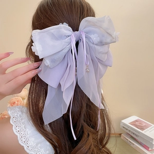 Dettaglio di una grande pinza per capelli color lavanda con fiocco in organza e fiori
