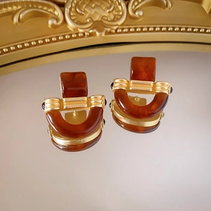 Macro view of vintage resin earrings with gold metal frame on reflective mirror surface