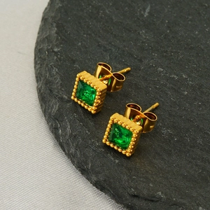 Square green zircon gold stud earrings with beaded frame on a stone surface