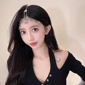 Close-up of silver boho headpiece with hollow metal patterns and tassel drops on forehead