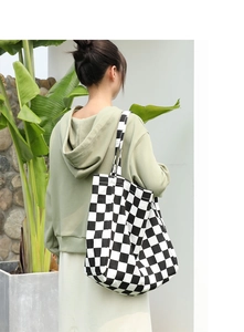 Shoulder shot of a black and white checkerboard canvas tote bag for daily casual use