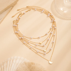 Close-up of multilayered gold necklace with pearls and heart moon star charms