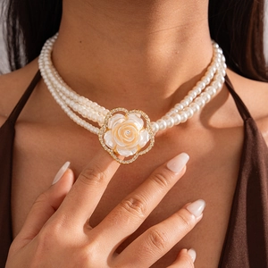 Detail of multi-layer pearl sweater necklace with elegant rose flower pendant on model