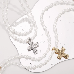 Detailed macro view of vintage cross pendants and white pearls with unique metallic texture