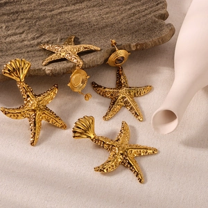 Golden starfish and shell earrings in stainless steel on natural stone background