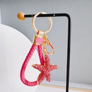 Close-up of pink rhinestone starfish pendant with braided leather keychain and gold details