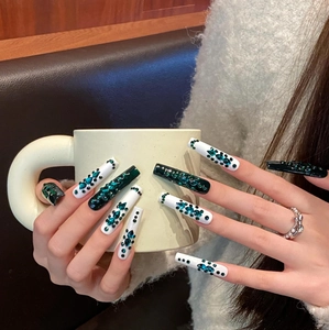 Detailed view of long coffin-shaped green and white handmade press-on nails with crystals