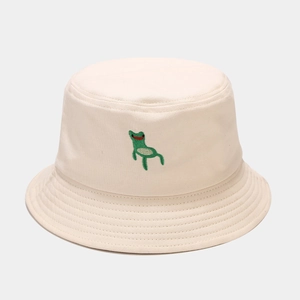 Close-up of fine green frog embroidery and parallel stitching on a cream cotton bucket hat