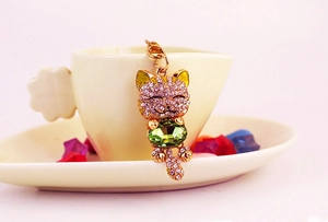 Macro view of crystal lucky cat keychain with purple rhinestones and green gemstone