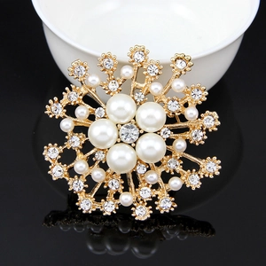 Close-up of golden snowflake brooch with pearls and crystals on reflective black surface