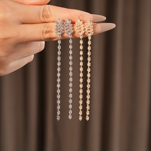 Detail of elegant wheat ear tassel earrings in gold and silver with zircon stones