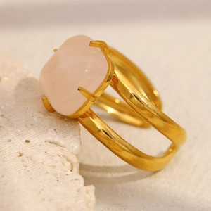 Détail d'une bague plaquée or 18K avec pierre précieuse carrée rose sur fond de pierre